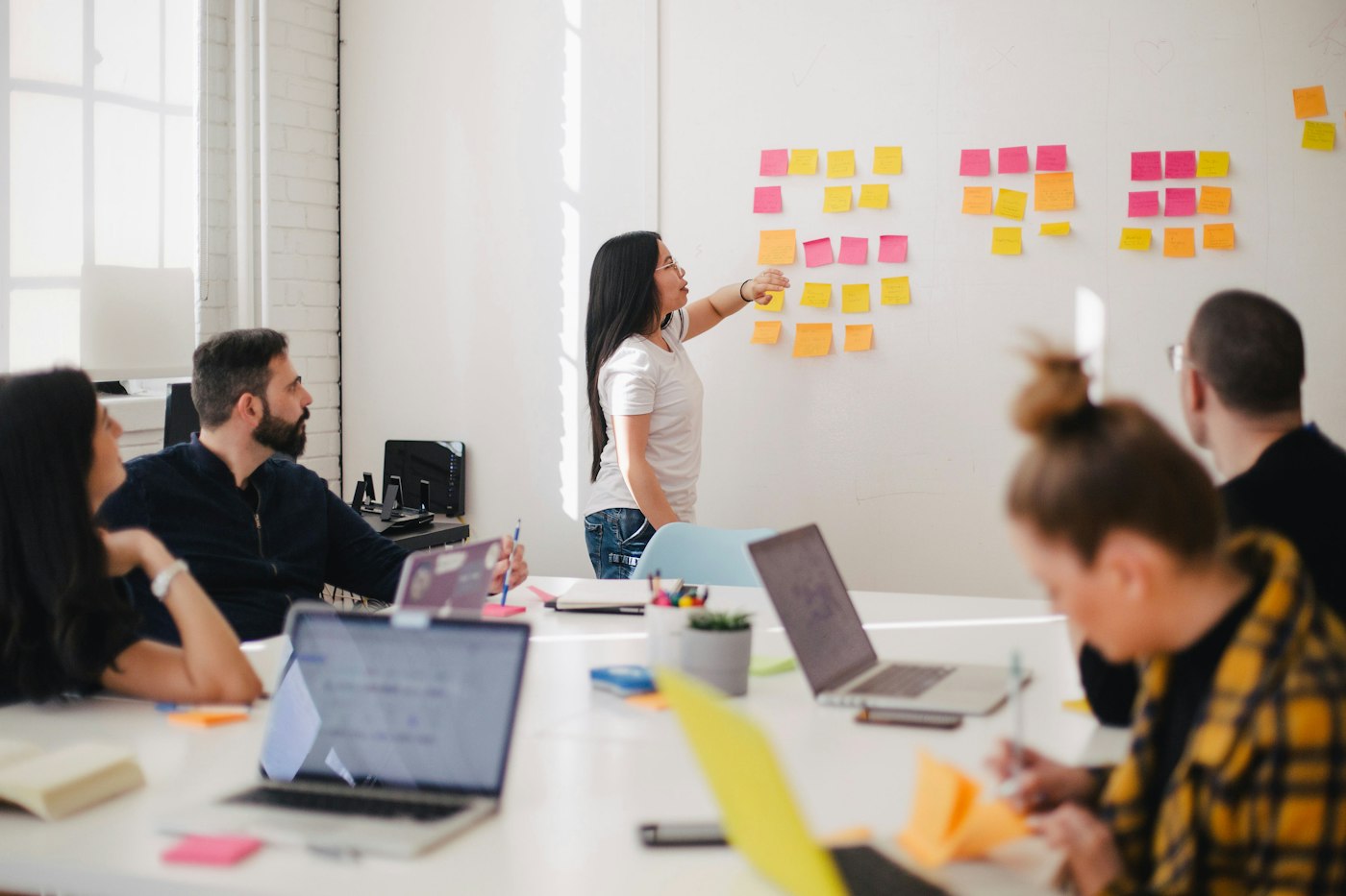 Equipo reunido en una oficina, trabajando con ordenadores portátiles y revisando un panel de planificación