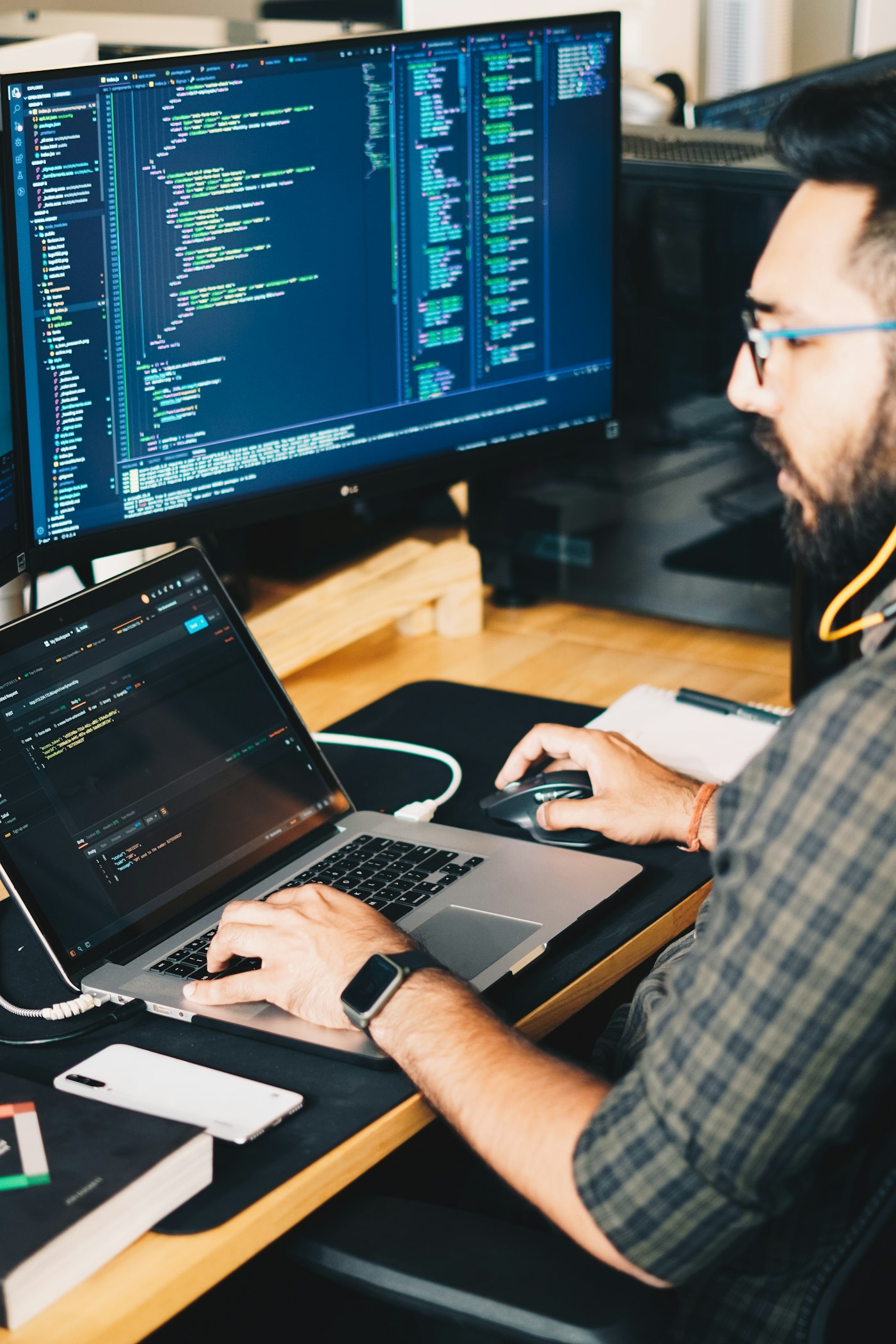 Puesto de desarrollo con código en un portátil y un monitor